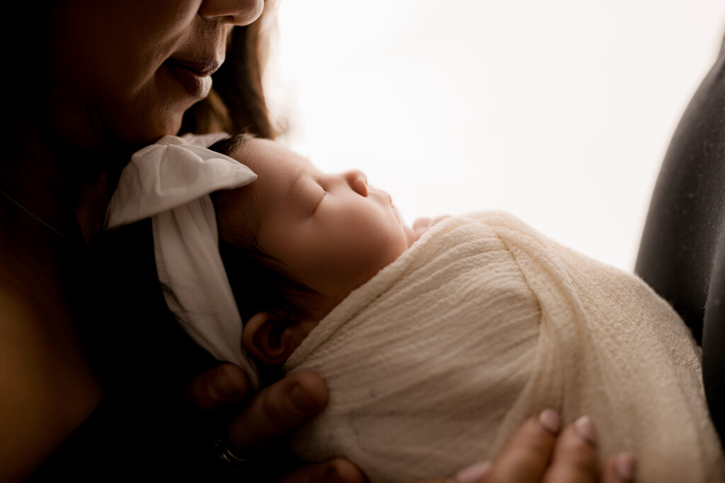 baby in white swaddle while mom holds her 