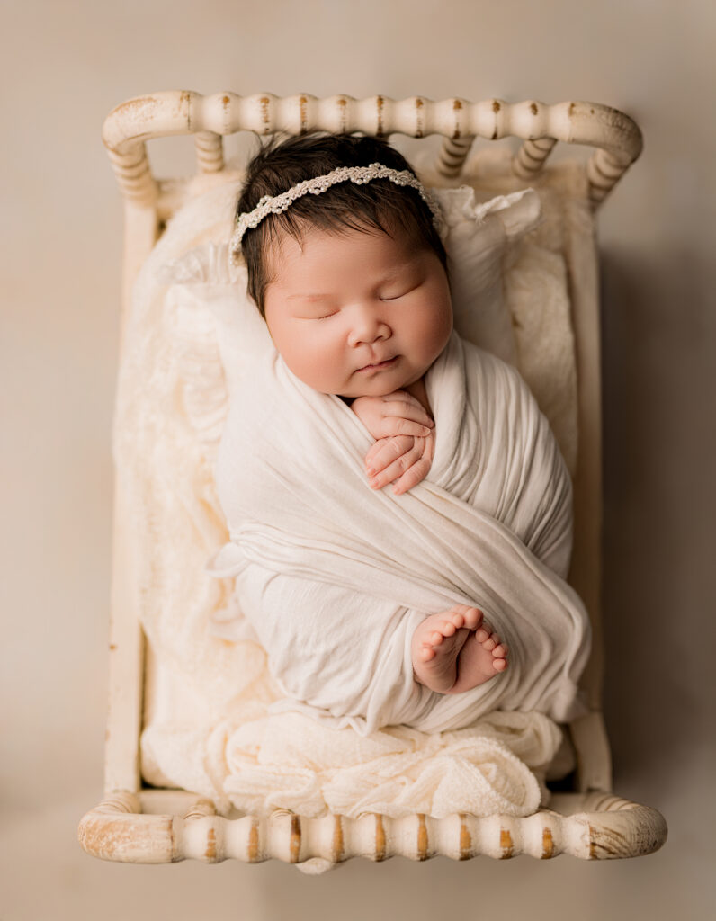 Baby wrapped in a white swaddle with toes showing 