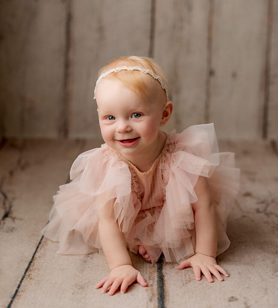 ^ month baby girl in a pink tulle dress crawls towards camera 