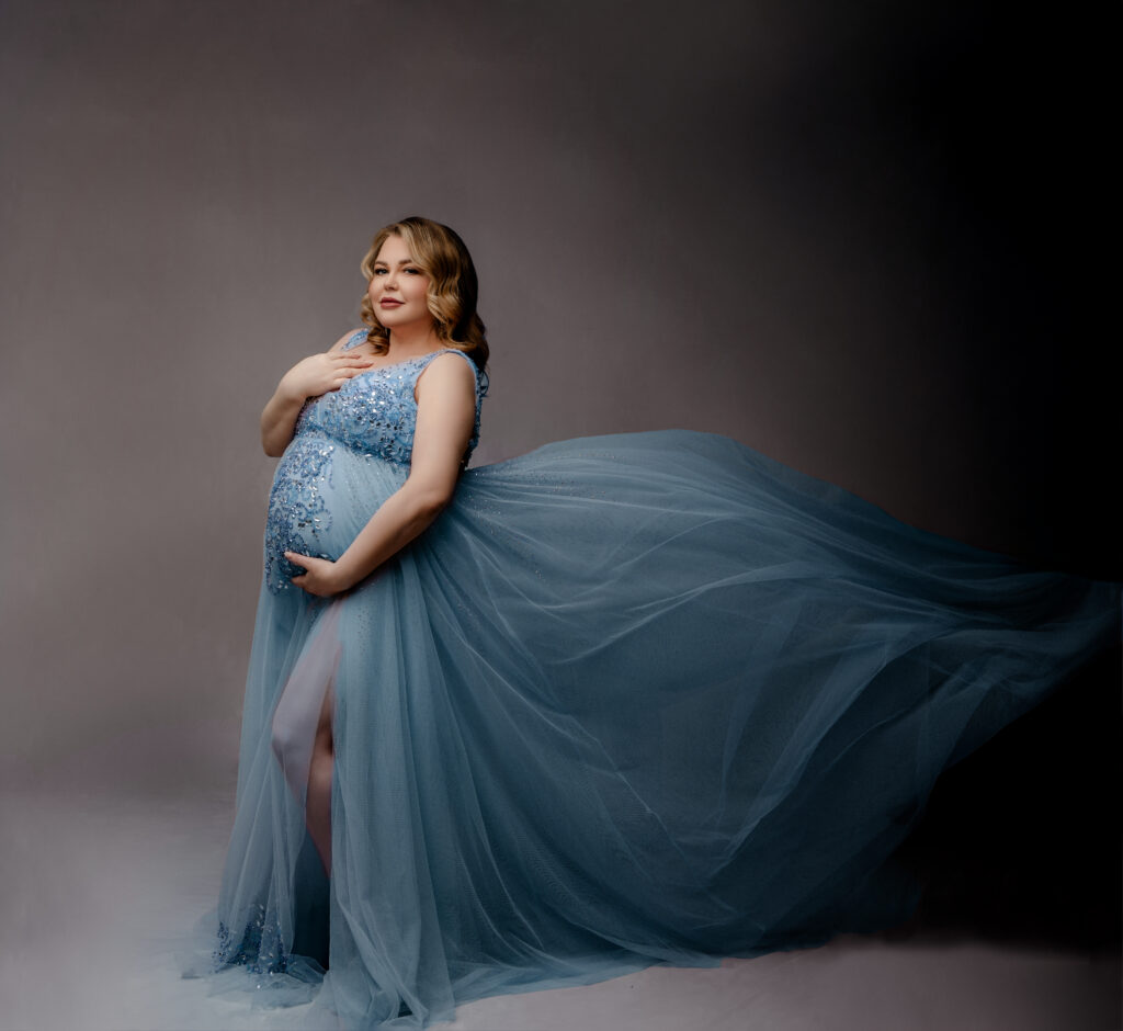 pregnant mother poses in blue teal dress at Studio maternity session in Austin